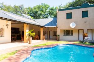 a house with a swimming pool in front of a house at Guest Paradise Lodge in Victoria Falls