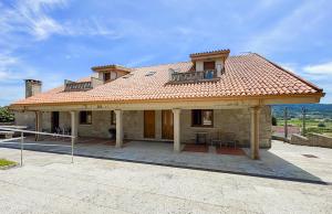 a large house with a roof with a balcony at A casa dos Viñedos, finca con piscina privada in Bayón