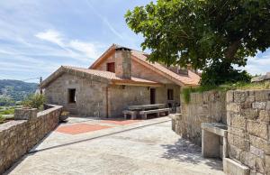 a stone house with a bench in front of it at A casa dos Viñedos, finca con piscina privada in Bayón