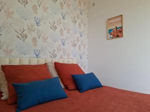 a bed with two blue and red pillows in a room at Le chalet Ker Yann Vue mer Locquirec in Locquirec