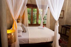 a bedroom with a bed with white curtains and a window at Beverly Suites - Two Bedroom Apartment 2-5min to Beach in Malindi