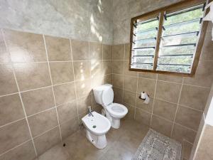 a bathroom with a toilet and a window at Beverly Suites - Two Bedroom Apartment 2-5min to Beach in Malindi +8 photos