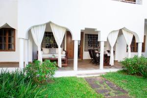a white house with a patio with a table at Beverly Suites - Two Bedroom Apartment 2-5min to Beach in Malindi
