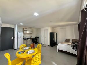 a room with a table and yellow chairs and a bed at Flat no bairro universitário in Caruaru