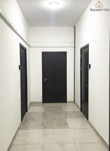 a hallway with two black doors and a tile floor at Bazaleti Hut in Bazalet'i +9 photos