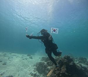 a person in the water with a camera on a reef at Feelgood dive resort in Basbas