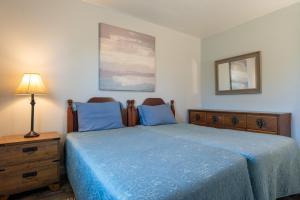 ein Schlafzimmer mit einem Bett mit blauer Bettwäsche und einer Lampe in der Unterkunft Wood Duck Cottage in Cavendish