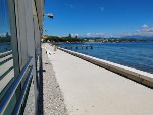 a person walking down a sidewalk next to the water at Garda Rooms in Desenzano del Garda