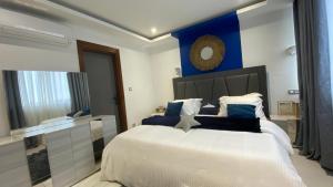 a bedroom with a large white bed with blue walls at Appartement Meublé HS Bonanjo in Douala