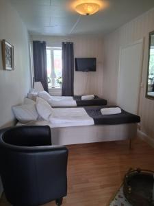 a hotel room with two beds and a chair at Skärplinge Gästis B&B in Skärplinge