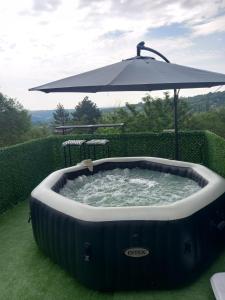 a hot tub with an umbrella in the grass at Vikendica Miličin Konak in Vrdnik
