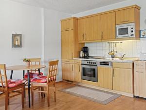 a kitchen with wooden cabinets and a table with chairs at Apartment Düneneck App-17 by Interhome in Zempin