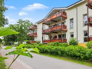 an apartment building with red balconies and a sidewalk at Apartment Düneneck App-17 by Interhome in Zempin
