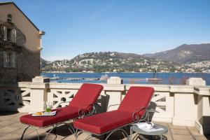 two red chairs on a balcony with a view of the water at Albergo Terminus in Como