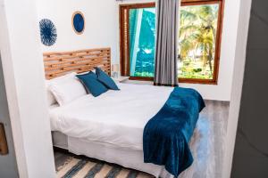 a bedroom with a large white bed with blue pillows at Giraffe House Vilankulo in Vilanculos