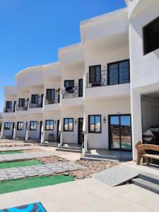 a large white building with windows and a swimming pool at Playa Hotel in Dahab