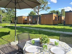 a table with plates and an umbrella in a yard at Holiday Home Tiny Haus Libelle by Interhome in Riedenburg