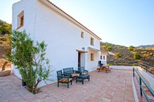 a patio with chairs and tables on a white building at Campo and relax Málaga country house in Málaga