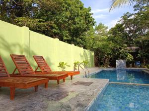 two wooden chairs sitting next to a swimming pool at Wilpattu Wild Villa in Pahala Maragahawewa
