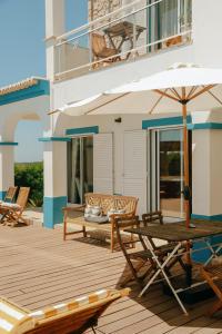 a wooden deck with a table and chairs and an umbrella at Arrifana Destination Suites in Aljezur