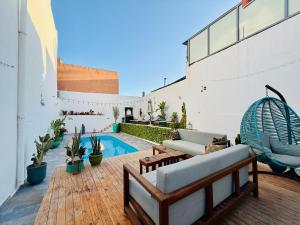 an outdoor patio with a pool and chairs and plants at Dar Surfana Surf Camp & Yoga Tamraght in Aourir