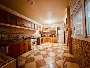 a kitchen with wooden cabinets and a tile floor at Dar Surfana Surf Camp & Yoga Tamraght in Aourir