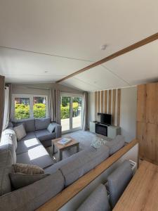 a living room with a large couch and a tv at Inverbeg Holiday Park in Luss