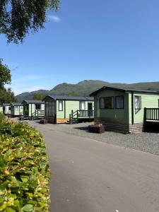 a row of green cabins with mountains in the background at Inverbeg Holiday Park in Luss