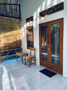 a porch with a wooden door and a wooden chair at Lomba Oen bungalow in Nembrala