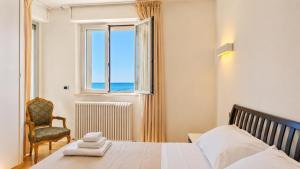 a bedroom with a bed and a chair and a window at SkyMare - Beachfront Sea View Apartment in Porto San Giorgio