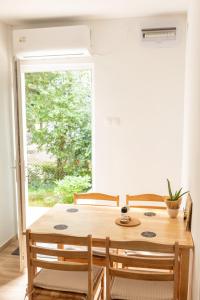 a dining room table with four chairs and a window at Flóra Vendégház Balatonvilágos in Balatonvilágos