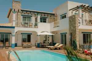 a villa with a swimming pool and a house at Arrifana Destination Suites in Aljezur