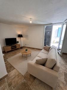 a living room with a couch and a tv at Le Petit Nid de Venelles in Venelles