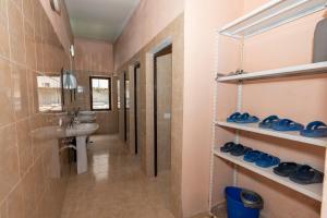 a bathroom with a sink and blue shoes on shelves at Hotel Shen Klementi in Vermosh