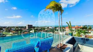 a swimming pool on the roof of a building with a palm tree at Makani Beach Campas - Praia de Tamandaré in Tamandaré
