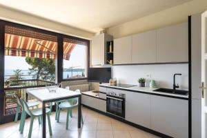a kitchen with white cabinets and a table with chairs at Latte & Menta by Garda FeWo in Gardone Riviera +19 photos