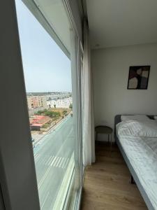 a bedroom with a bed and a large window at Charming apt with terrace in Kenitra