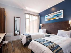 a hotel room with two beds and a desk and a mirror at Aggeneys Hotel in Aggeneys +14 photos