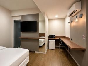 a hotel room with a bed and a desk with a television at Premium Executive Hotel Itabira in Itabira