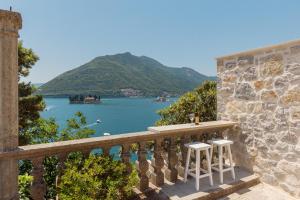 a balcony with two white stools and a view of the water at Step to Kotor bay Perast in Perast
