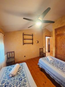 a bedroom with two beds and a ceiling fan at Casa Rural La Vid in Cadalso de los Vidrios
