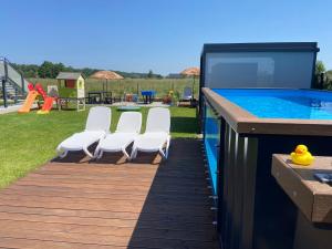 a deck with chairs and a swimming pool at Apartamenty Czerwone Korale in Chłopy