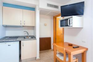 a kitchen with a sink, microwave and refrigerator at Apartamentos Mar y Playa in Ibiza Town