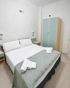 a bedroom with a large white bed with towels on it at Hotel Ristorante Selene in Alba Adriatica