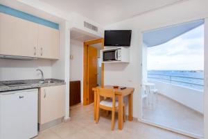 a kitchen with a table and chairs and a refrigerator at Apartamentos Mar y Playa in Ibiza Town