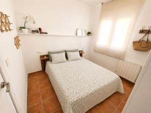 a small white bedroom with a bed and a window at Chalet con piscina y barbacoa, Valencia in Torrent