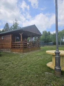 a wooden cabin with a picnic table in a field at Domek skandynawski in Łuszczewo