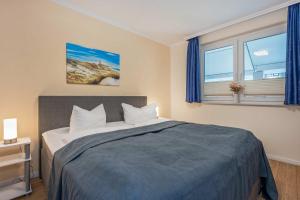 a bedroom with a bed with blue sheets and two windows at Ückeritz Sylva in Ueckeritz