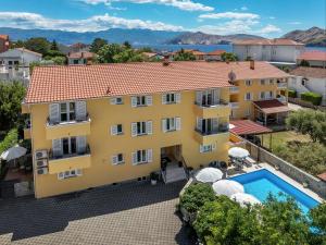 an aerial view of a yellow building with a swimming pool at House Gorica 2 - underground level apartments in Baška