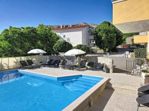 a swimming pool with chairs and umbrellas on a patio at House Gorica 2 - underground level apartments in Baška
